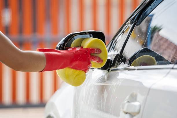 istock hand holding sponge washing side mirrors of a car 1258654004