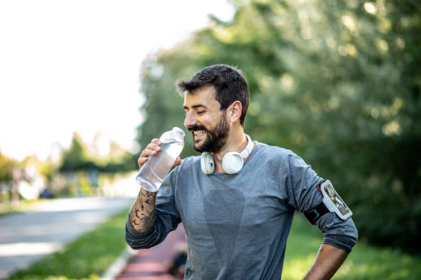 istock The man runs in nature and make pause on the treadmill, smiling and drinks water 1258659334