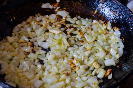 Sauteed onions in pan. Frying finely chopped onions. Simple homemade food. Cooking. Top view at an angle. Selective focus.