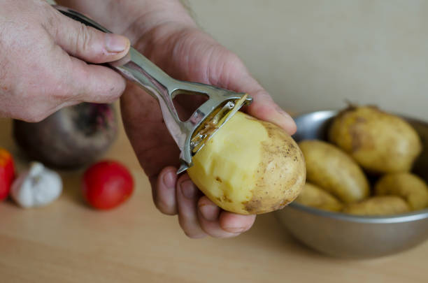 istock Middle-aged man peels raw potatoes. 1258680196