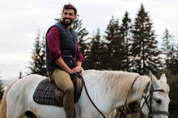 istock a handsome man rides a beautiful white horse in a mountain forest 1258733947