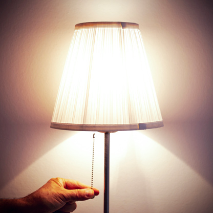 a male hand pulls the chain of an old-fashioned bedside lamp. turn off the light, find rest, sleep.