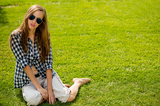 Beautiful woman wearing sunglasses in summer park