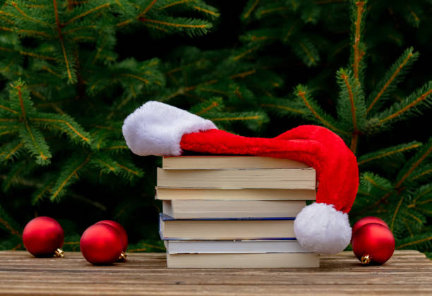 istock Santa Claus hat and books on wooden table with spruce branches on background 1258772439