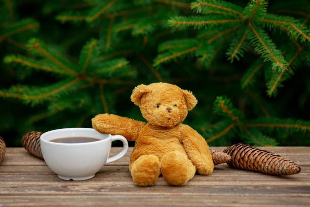 istock cup of coffee and teddy bear on wooden table with spruce branches on background 1258773105