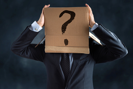 Businessman with drawn question mark on cardboard box over his head