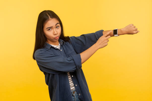 jest późno, pospiesz się! portret niezadowostnej zapracowanej kobiety w dżinsowej koszuli wyglądającej niecierpliwie i wskazującej na zegarek - checking the time zdjęcia i obrazy z banku zdjęć