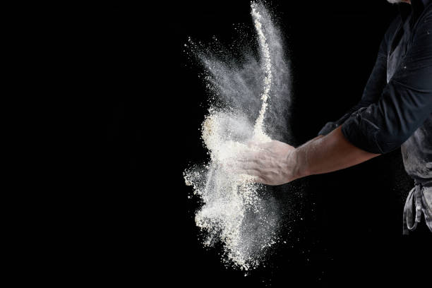 istock chef in black uniform sprinkles white wheat flour in different directions 1258843666