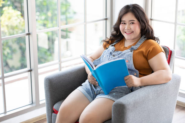 istock Chubby woman reading a book on free time 1258891155