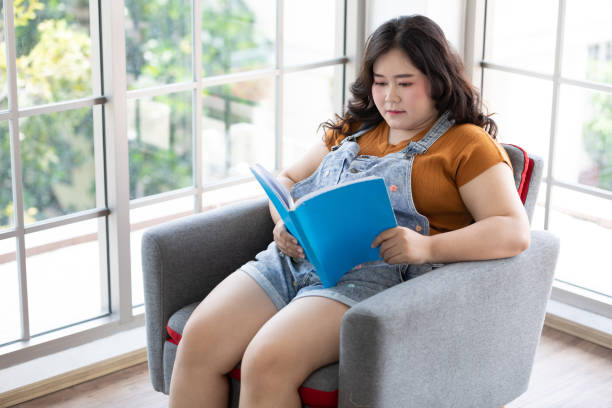 istock Chubby woman reading a book on free time 1258891156
