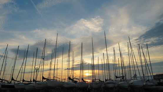 Hayama, Japan - September 8, 2019: Privately owned yachts lined up in a row at Hayama Marina at a beautiful sunset. The wind from the sea makes clattery sounds of masts of the yachts. It's a beautiful and calm harbor resort not far from the center of Tokyo.
