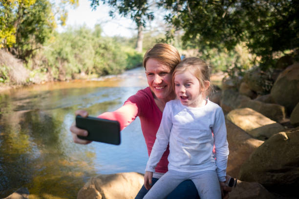istock Mother and daughter taking a fun selfie by the river 1258920505