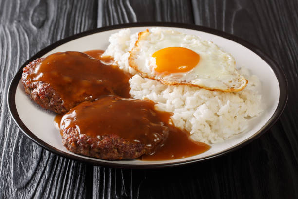 istock loco moco is a Hawaiian cuisine made with white rice with a hamburger patty, sunny side up egg, and brown beef gravy close-up on a plate. Horizontal 1258945366