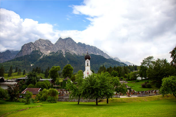 grainau, bawarska wioska. kopułą kościoła św johannes, cmentarz z górami (waxenstein i zugspitze szczyty). wetterstein zakres północne alpy wapienne bayern niemcy europa. staw na pierwszym planie - waxenstein zdjęcia i obrazy z banku zdjęć