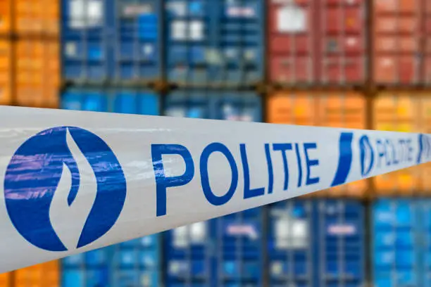 War on drugs. Politie / police tape in front of stacked containers waiting for transport on the quay at Belgian port / harbour in Belgium