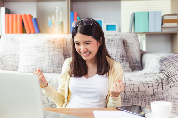 joven mujer asiática emocionada se siente eufórica celebrando la victoria en línea exitosa del resultado del logro. feliz joven recibir buenas noticias por correo electrónico, motivado por una gran oferta o nueva oportunidad, obtener un buen trabajo - i love my job fotografías e imágenes de stock