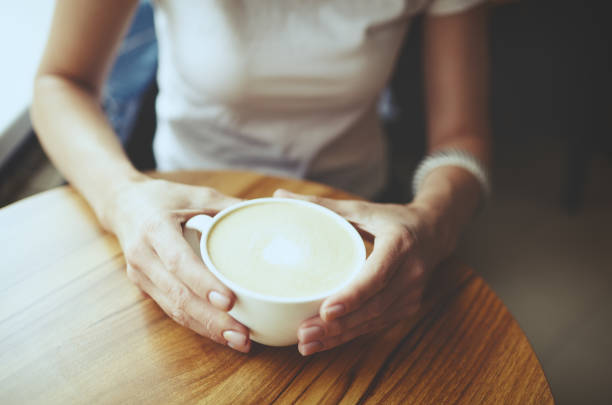 istock Female hands holding cup of coffee in cafe. Blurred image, selective focus 1258968647