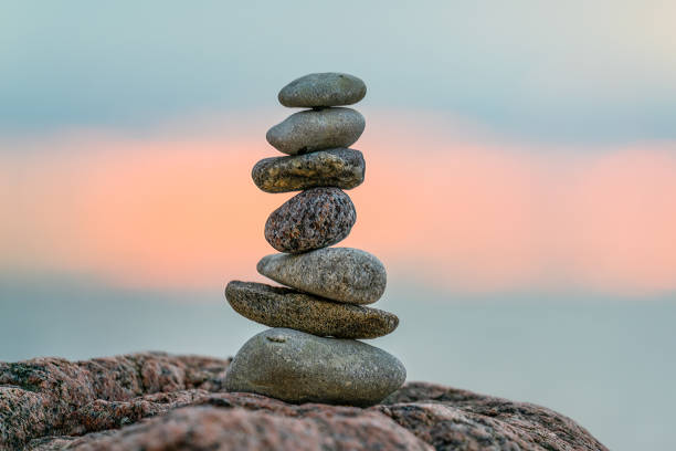A small cairn placed on a rock at sunset A small cairn placed on a rock at sunset  with the sun setting in the background cairns photos stock pictures, royalty-free photos & images