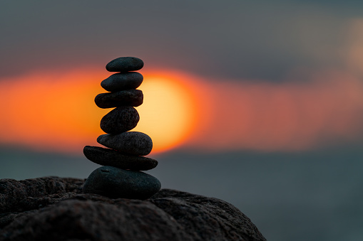 A small cairn placed on a rock at sunset  with the sun setting in the background