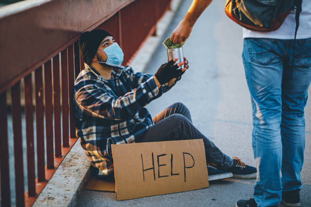 Homeless man with cardboard sign receiving money donation Young homeless man with cardboard sign receiving money donation beg alms stock pictures, royalty-free photos & images