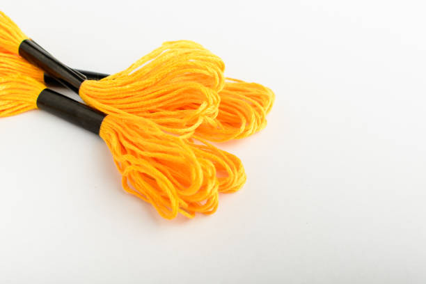 istock Three vivid yellow sewing threads for embroidery isolated on a white table, side view of textile materials 1259036679