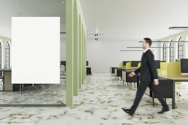 istock Businessman walking in office interior with blank poster 1259036786