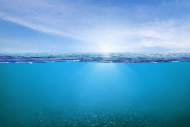 blue under water waves and bubbles. beautiful white clouds on blue sky over calm sea with sunlight reflection, - under the surface imagens e fotografias de stock