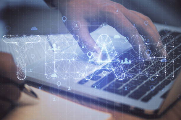 istock Hand using laptop with glowing polygonal team hologram 1259036982