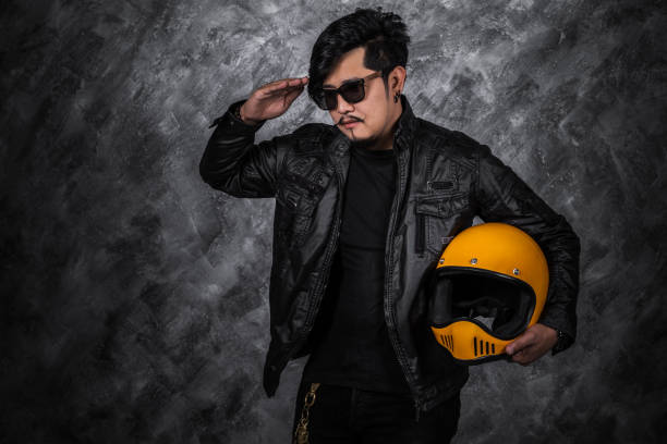istock biker man in black leather jacket saluting and holding helmet 1259072188