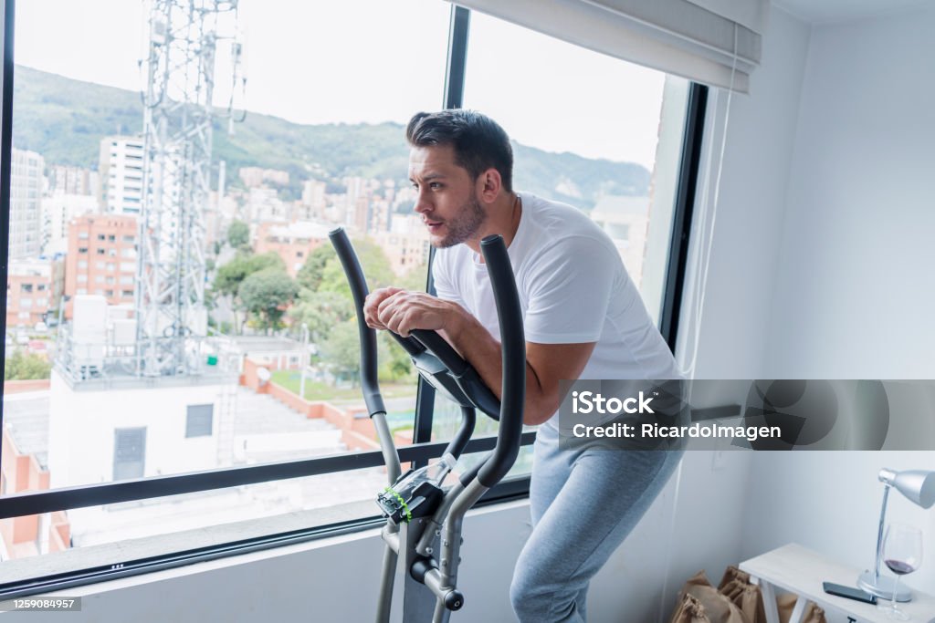Latino Man Exercising At Home On An Elliptical During The Covid 19 Stock  Photo - Download Image Now - iStock