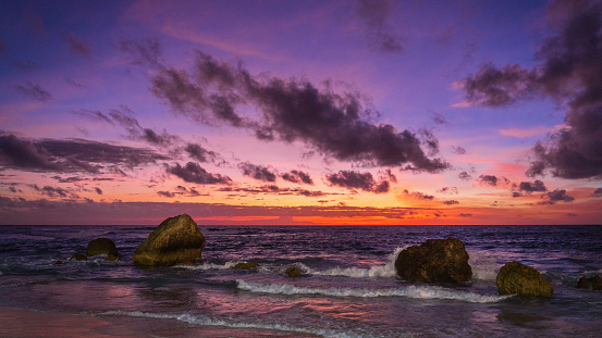 Dramatic colorful vibrant sunset skyscape over the coastal rocks at natural Sumba Nihisumba Beach. Indian Ocean Waves splashing towards the natural exotic dream beach under colorful pink sunset twilight. Panorama XXXL. Nihisumba Beach, Sumba Island, Nusa Tenggara Timur, Indonesia, Southeast Asia