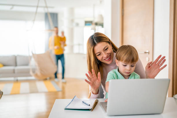 istock Happy family at home using computer, waving while in a live video chat 1259134513