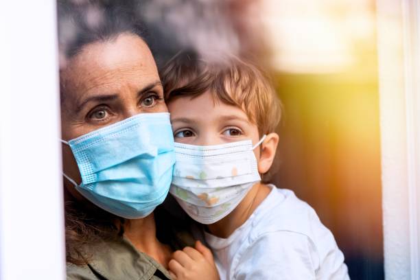 istock Mature woman posing with her son, both with protective masks, very sad looking through window worried about loss of her job due Covid-19 pandemi 1259134620
