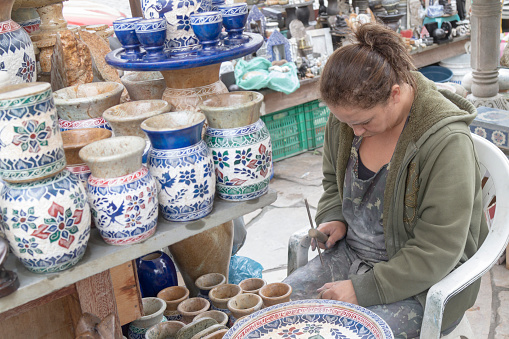 June 26, 2019 - Ouro Preto, Minas Gerais, Brazil: A female Handcraft Artist sculpting a pot in a street market in Colonial City Town of Ouro Preto, Minas Gerais, Brazil in a cloudy winter day\n\nOuro Preto is a former colonial mining town in Minas Gerais, designated a World Heritage Site by UNESCO.\n\nFounded in latest 17th century, Ouro Preto means in english \