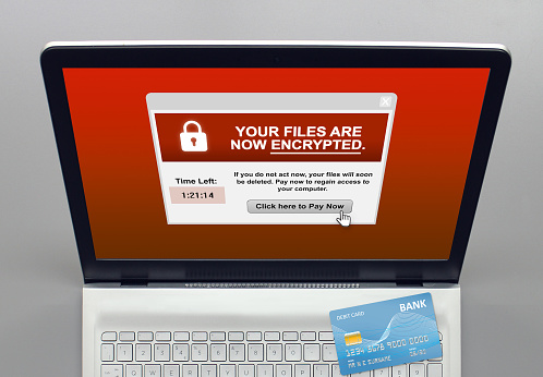 A laptop infected with Ransomware, a fictional payment card in view ready to make payment