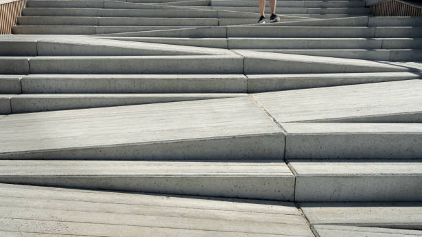 Concrete staircase and ramp way. Stairway designed for use of both pedestrians and disabled people or parents with prams. Human legs going downstairs stock photo