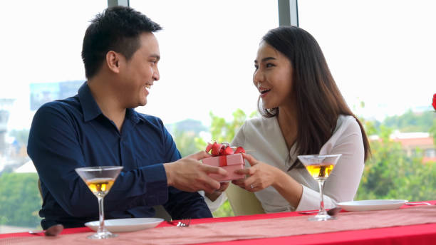 istock Romantic couple giving gift to lover at restaurant 1259150286
