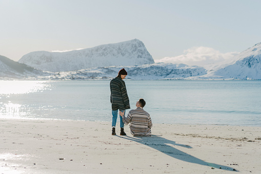 Woman and man sitting  on seaside in winter on Lofoten island