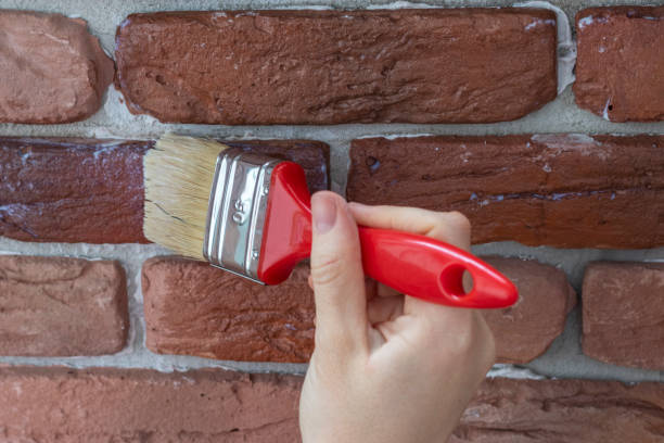 Female hand applies varnish to decorative facing brick. stock photo