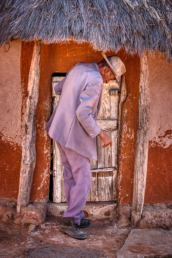 portrait of an old african man opening the door to his house  village in a botswana