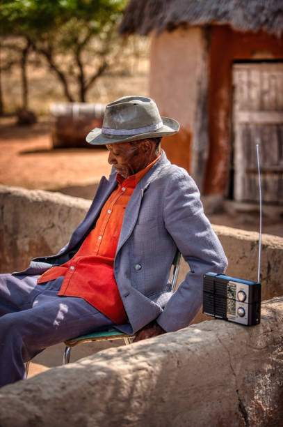 portrait of an old african man portrait of an old african man listening to his radio in a village in a botswana old person listening to radio stock pictures, royalty-free photos & images
