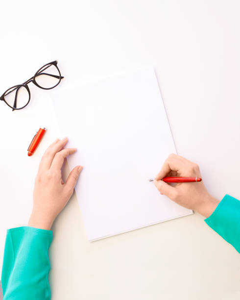 istock Top view of female hand is writing blank paper on white table 1259178763