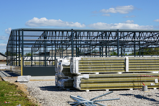 construction of a new modern industrial building, metal truss frame on a background of blue sky