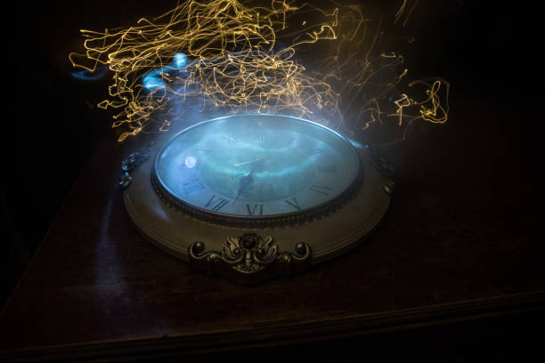 istock Time concept. Big vintage round clock on wooden table with abstract light. 1259211732