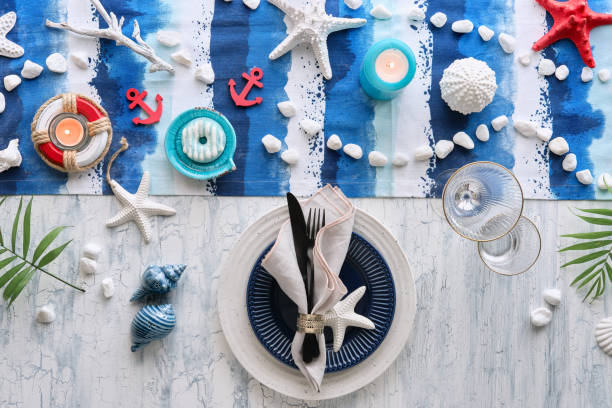 istock Contemporary summertime table setting with nautical sea decorations on blue and white stripy runner, classic blue white plates, utensils on white rustic table. Top view, casual modern lunch. 1259225156