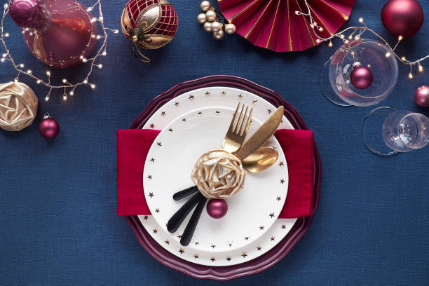 istock Christmas table setup with golden utensils, red deco. Flat lay on classic blue linen textile table. 1259246709