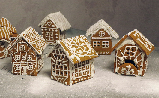 Gingerbread houses with cream frosting and sugar icing displayed for festive catering buffet among other variety of different sweets and desserts.