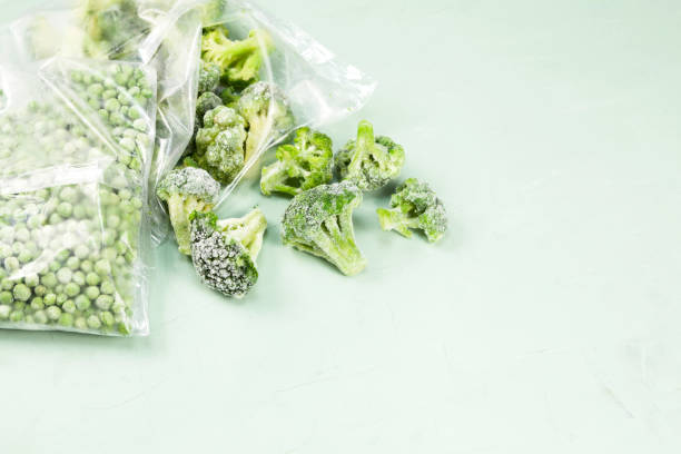 istock Frozen vegetables on a light background with copy space. Green peas and broccoli in transparent bags. Reserve vitamins for the winter 1259265141