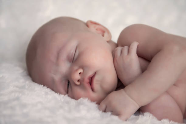 istock Newborn baby sleeps sweetly on light background 1259270871