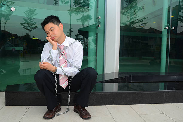Unhappy worker being chained to work stock photo